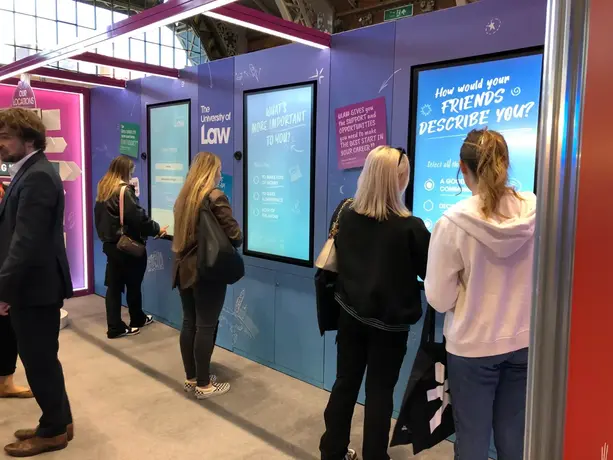 Students using touchscreen quizzes on The University of Law's interactive exhibition stand