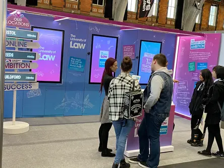 Students at The University of Law's recruitment stand with interactive screens